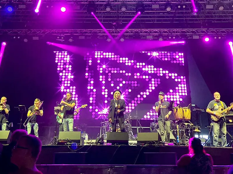 Brass Monkees 9-piece band on a large outdoor festival stage with an LED wall and purple lights